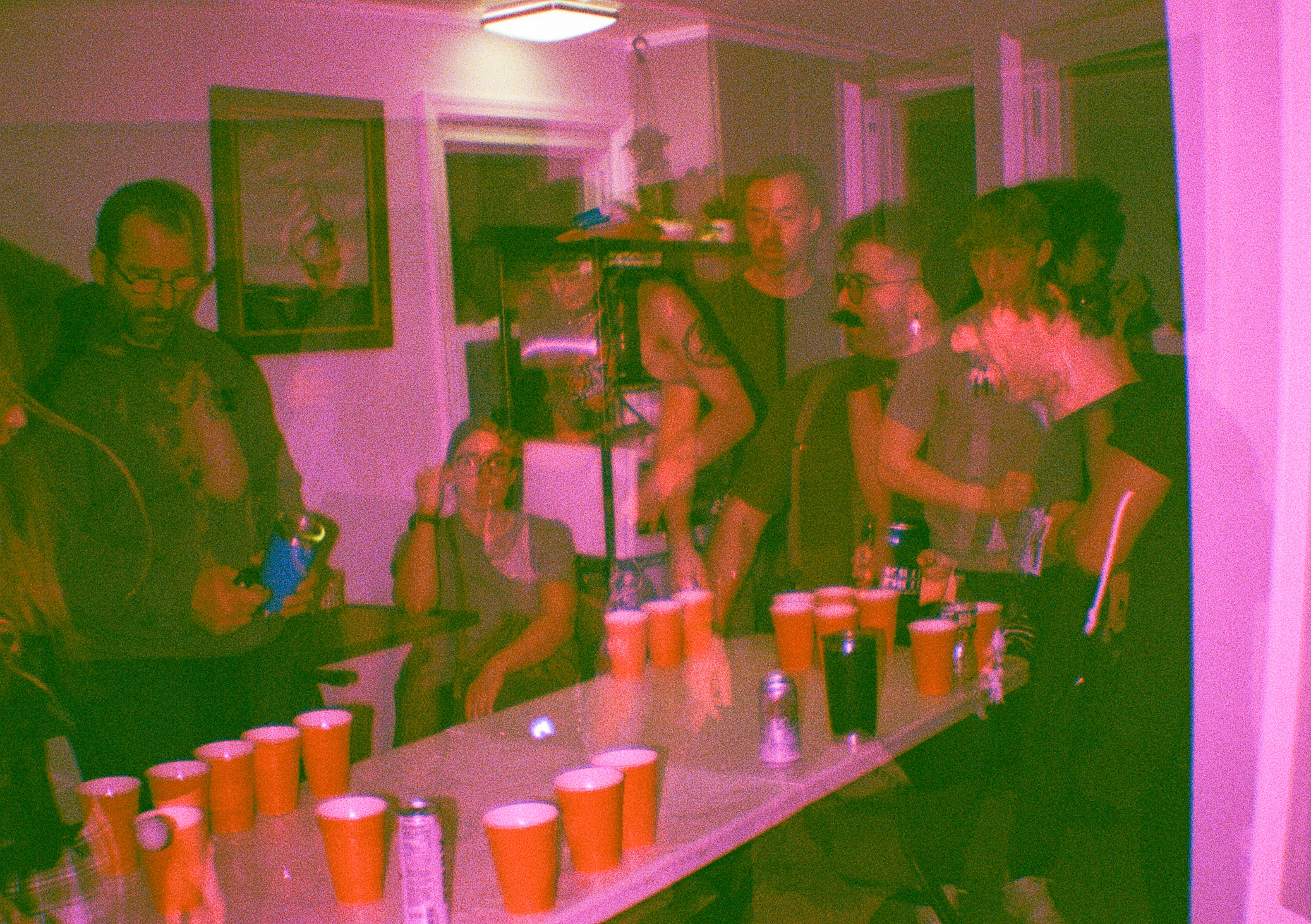 Double exposure film photo of people playing beer pong and dancing at a party